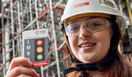 Mitarbeiterin hält Sicherheits-Karte in die Kamera